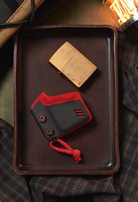 Zippo Black-Red handmade sheath displayed beside a brass lighter