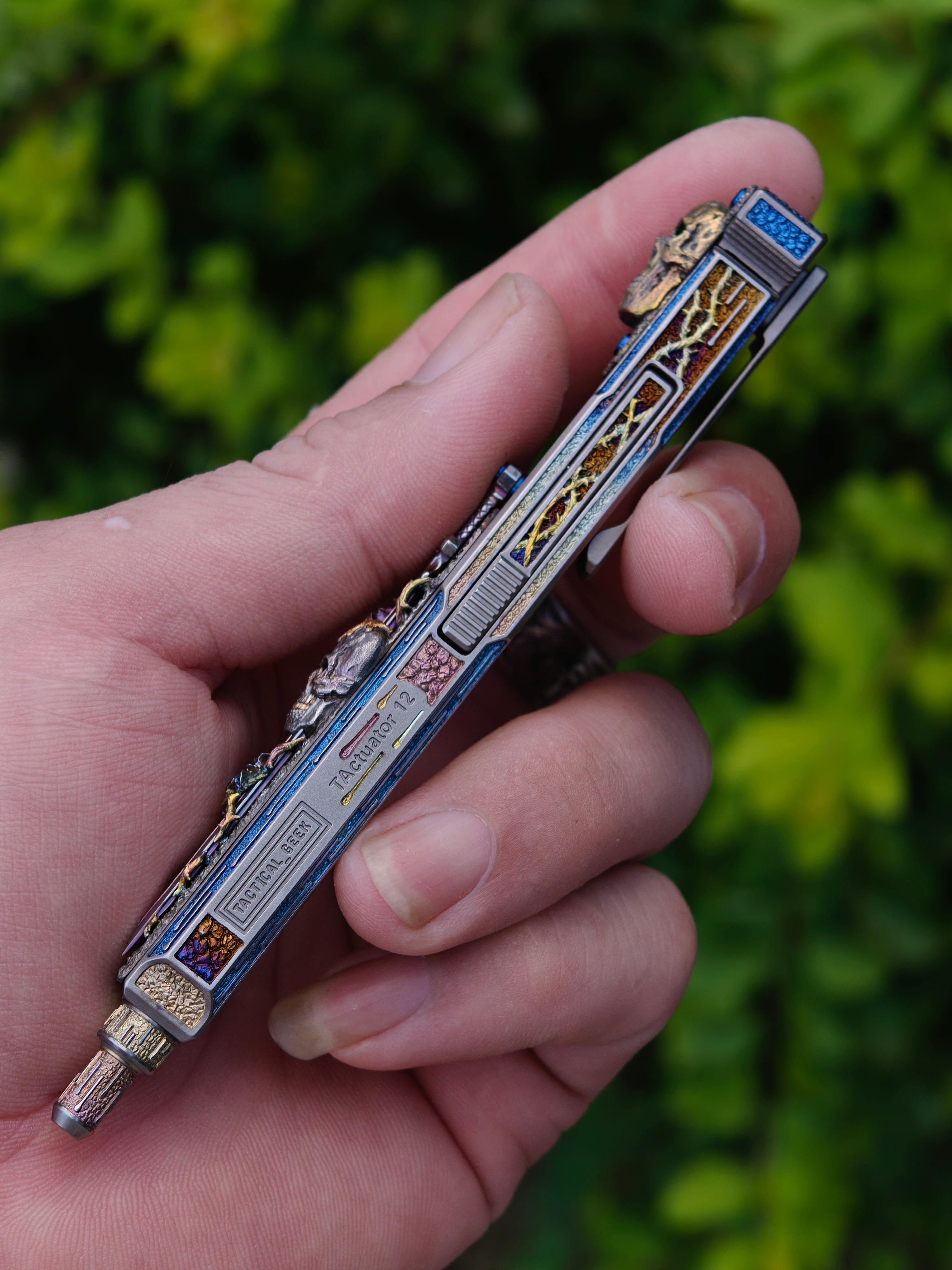 Blade of Bones engraved EDC pen held outdoors, reverse-side artwork