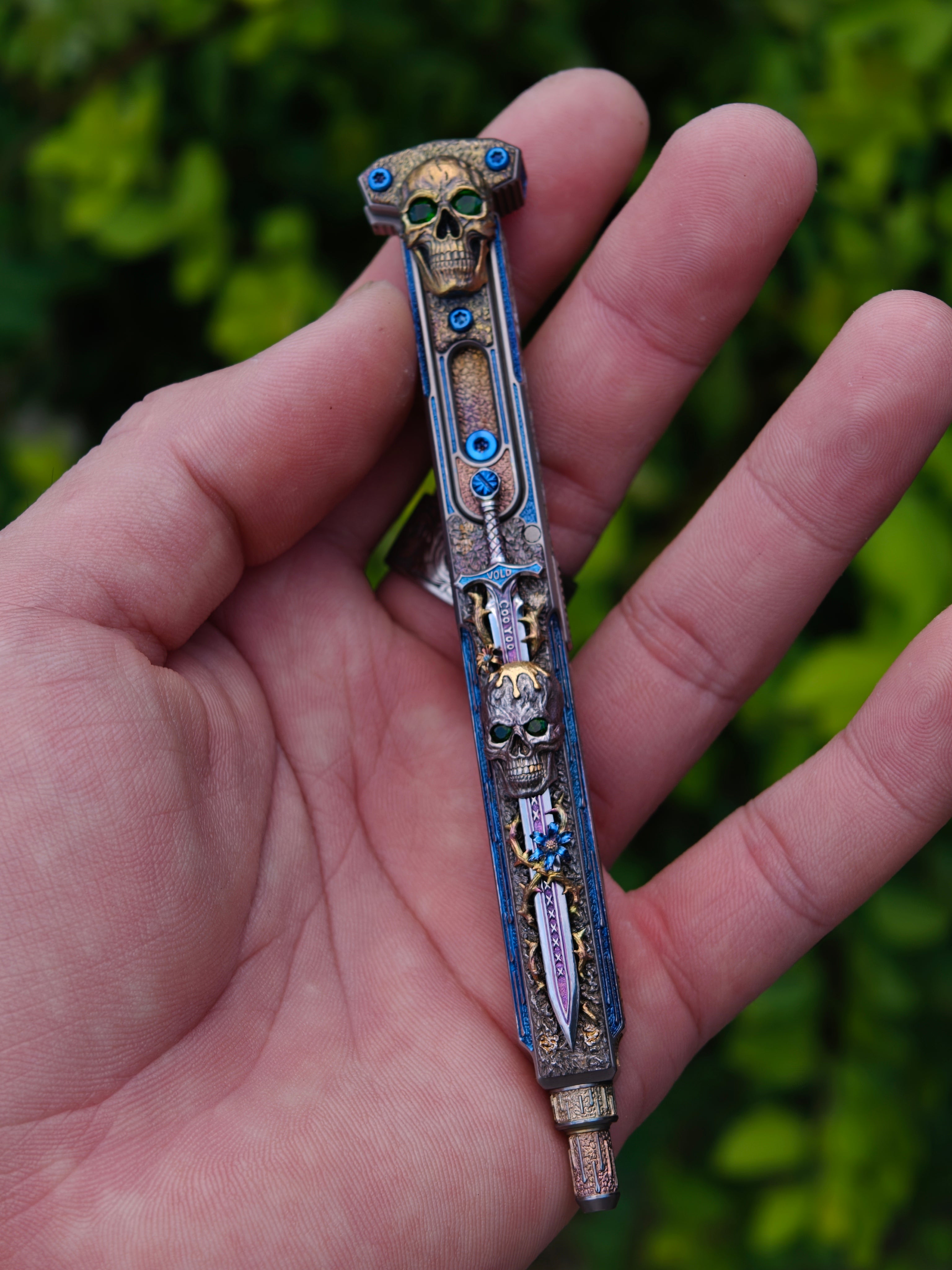 Blade of Bones engraved EDC pen held outdoors, skull artwork detail