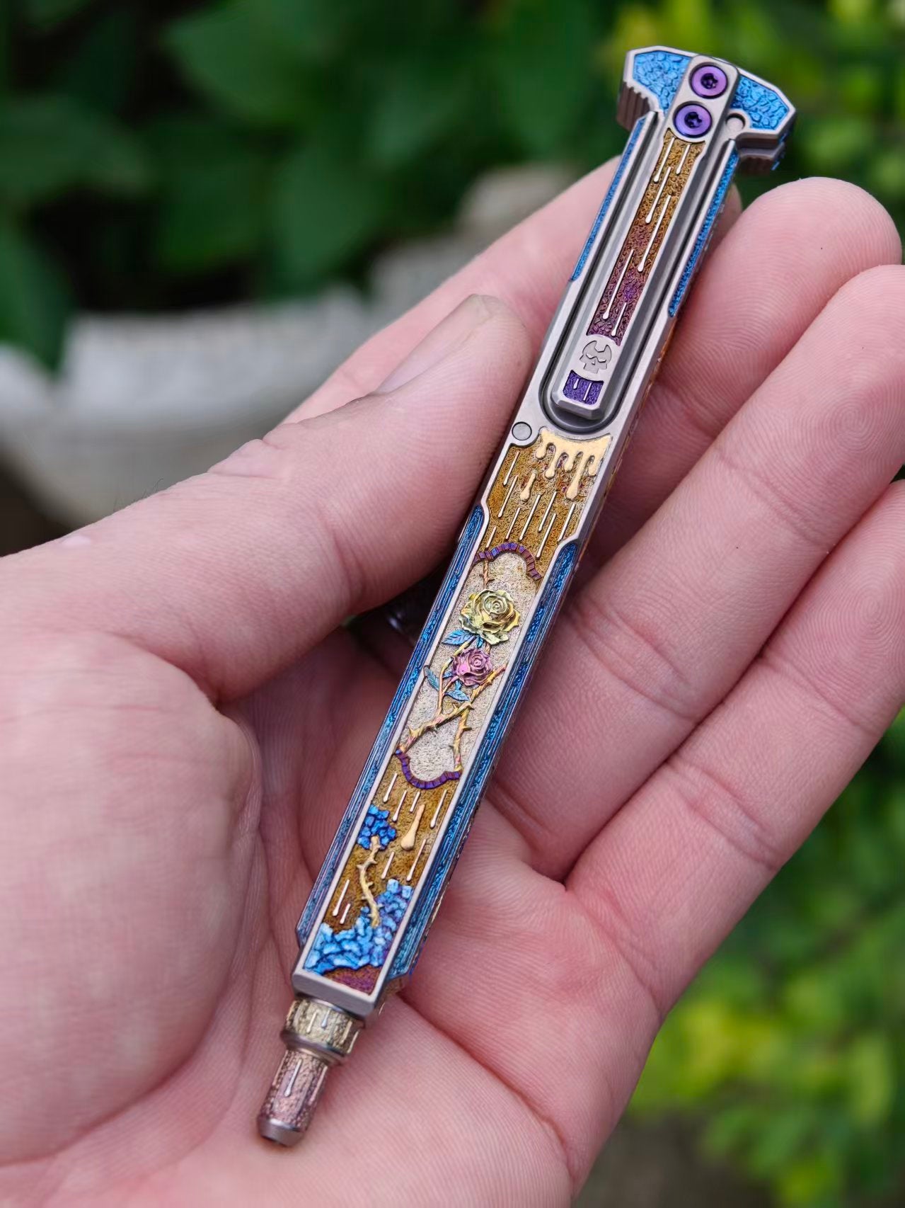 Blade of Bones engraved EDC pen held outdoors, clip-side view